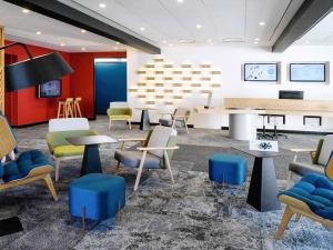 a waiting room with chairs and tables and a piano at Novotel Caen Côte de Nacre in Caen