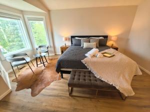 a bedroom with a bed and a chair and windows at Metta Stays Edgemont in Calgary