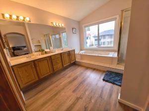 a bathroom with two sinks and a tub and a window at Metta Stays Edgemont in Calgary +38 photos
