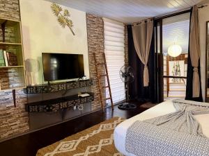 a bedroom with a bed and a television on a wall at Faaora Lodge, little paradise Moorea in Haapiti