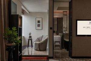a living room with a chair and a television at Rainbird Hotel in Chengdu