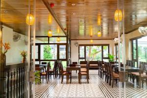 a dining room with tables and chairs and windows at Tam Cốc Hà Anh Hotel in Văn Lâm