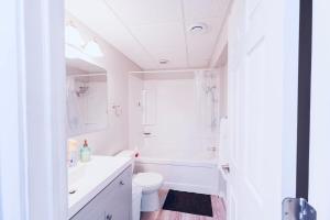 a white bathroom with a tub and a toilet and a sink at Cozy Prairie Mansion in Winnipeg +34 photos