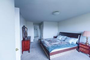a bedroom with a bed and a dresser with a lamp at Cozy Prairie Mansion in Winnipeg