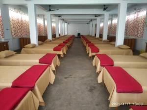a row of beds with red cushions in a room at Adharshila hotel & Dormitory in Shahdol