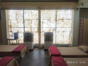 a room with two beds and two large windows at Adharshila hotel & Dormitory in Shahdol