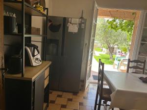 a kitchen with a refrigerator and a table and a door at Coatmeur brunette jean marie in Cabasse