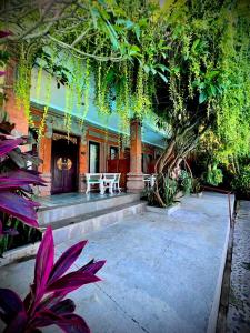 a house with a porch with a bench and trees at Ashyana Candidasa Beach Resort in Candidasa
