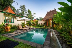 a swimming pool in front of a house with an umbrella at Juwel Villa Ubud in Ubud +16 photos