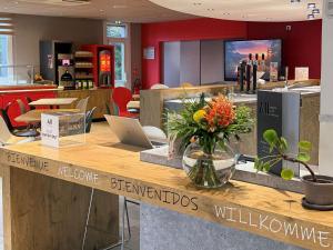 a restaurant with a counter with flowers on it at ibis Rennes Cesson in Cesson-Sévigné