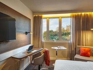a hotel room with a bed and a desk with a laptop at Novotel Sao Jose dos Campos in São José dos Campos