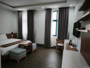 a hotel room with a bed and a table and a desk at Kakashi Hotel Phú Quốc in Phú Quốc