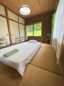 a large bed in a room with a large window at Homestay HANIHOHETO in Ena