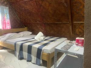 a bed with a blue and white striped sheets and a table at Sea Breeze Camp in Siquijor