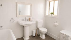 a white bathroom with a toilet and a sink at Verandah Suite in Seacliff +10 photos
