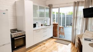 a kitchen with white cabinets and a balcony at Verandah Suite in Seacliff