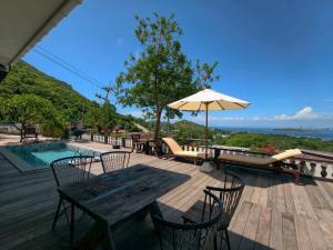 a wooden deck with a table and an umbrella at Baan Sahai Tone บ้านสหายโทน in Ko Larn