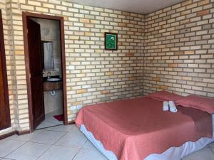a bedroom with a bed in a brick wall at Pousada Chalés do Cunhaú in Canguaretama