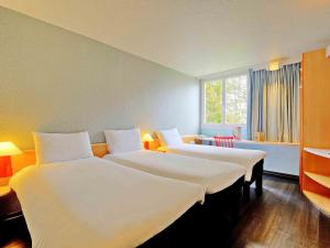 a hotel room with two beds and a window at ibis Poitiers Beaulieu in Poitiers