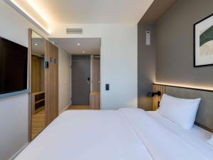a bedroom with a large white bed and a television at ibis Paderborn City in Paderborn
