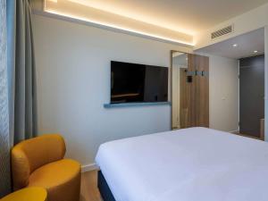 a bedroom with a white bed and two chairs at ibis Paderborn City in Paderborn