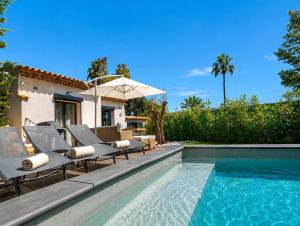 a pool with chairs and an umbrella next to a house at La petite maison in Mougins