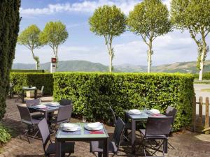 a patio with tables and chairs in front of a hedge at ibis Lyon Sud Saint-Rambert-d'Albon in Saint-Rambert-dʼAlbon
