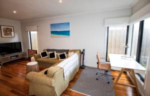 a living room with a couch and a tv at Flinders Rest in Queenscliff