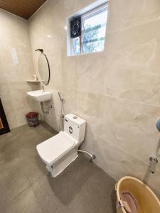 a bathroom with a toilet and a sink and a window at Mayura sea view in Malpe