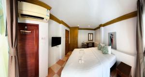 a bedroom with a large white bed and a television at Aura Hotel Phi Phi in Phi Phi Islands