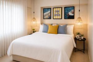 a bedroom with a white bed with blue and yellow pillows at Hotel Magnolia Boutique in Panama City