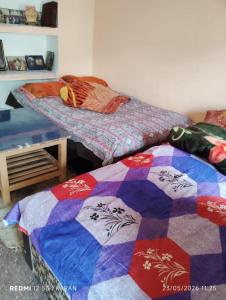 two beds in a room with a quilt at Chaukhamba hill homestay in Ukhimath