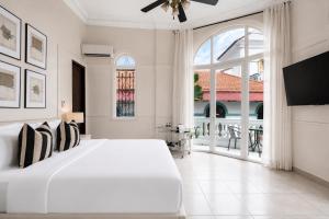 a white bedroom with a large bed and a large window at Hotel Magnolia Boutique in Panama City