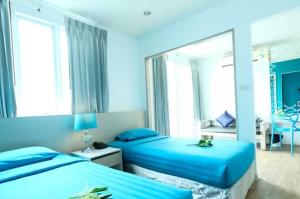 ein blaues Schlafzimmer mit zwei Betten und einem Spiegel in der Unterkunft Sunday Beachfront View Jomtien Pattaya in Jomtien Beach