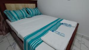 a bed with blue and white sheets and pillows at Sweet Inn Limbe in Limbe
