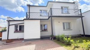 a white house with a balcony and a driveway at Domek 80m2 na wyłączność in Tczew