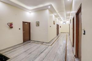 a hallway with white walls and a wooden floor at Super Hotel O Clock Tower Dehradun Formerly Dooncity Suites in Dehradun