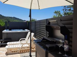 a patio with an umbrella and a grill with a table and chairs at Villa Marija Zaton in Dubrovnik