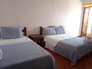 a room with two beds with blue and white sheets at Hotel Casona de San Pedro in Curití