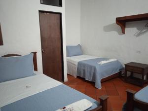 a room with two beds and a door to a bedroom at Hotel Casona de San Pedro in Curití