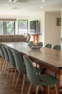 a large wooden table with green chairs in a room at the Lodge farm house in Hindmarsh Valley