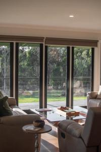 a living room with two couches and a large window at the Lodge farm house in Hindmarsh Valley