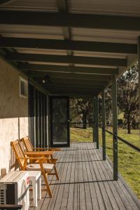 a porch with two wooden chairs and a table at the Lodge farm house in Hindmarsh Valley