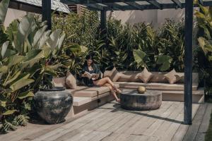 a woman sitting on a couch in a garden at MIZU Boutique Villas - Unique stay in Uluwatu in Uluwatu