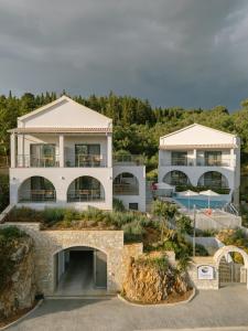 a large white house with a pool in front of it at Ostria Village in Syvota