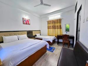 a hotel room with two beds and a desk at Lumbini Garden Lodge in Rummindei