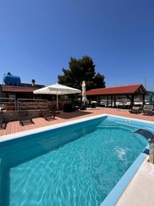 a blue swimming pool with a patio and umbrella at Beach house Sofia in Otok Žut +16 photos