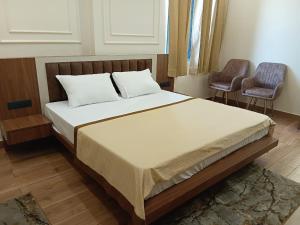 a bedroom with a large bed with two chairs at Hotel Shrivardhan in Sūratgarh +24 photos