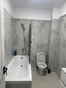 a bathroom with a bath tub and a toilet at Apartament Magnolia Panoramic in Craiova