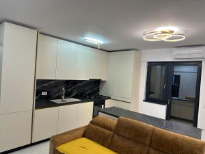 a kitchen with white cabinets and a couch in a room at Apartament Magnolia Panoramic in Craiova